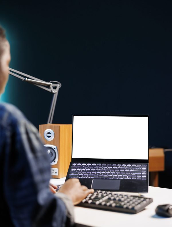 Black woman working from home at a desk with wireless computer displaying an isolated white screen. African american person using digital laptop showing blank chromakey mockup template.